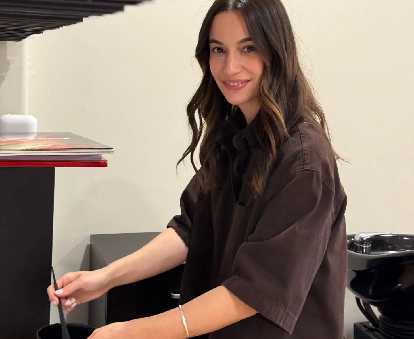 Georgia, SALON 28 stylist, smiling as she mixes hair colour in a black bowl at the salon